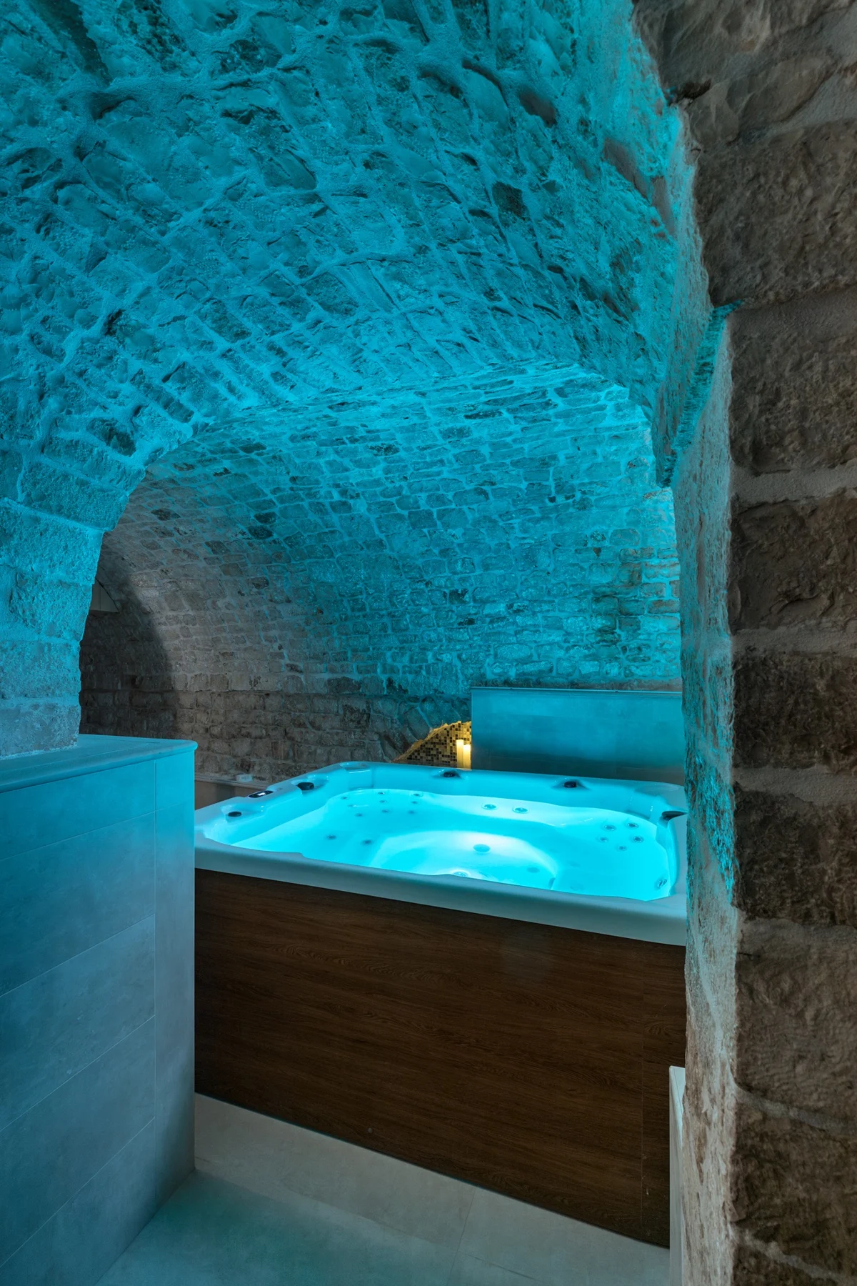 Piscina idromassaggio illuminata di azzurro nella SPA con volte in pietra